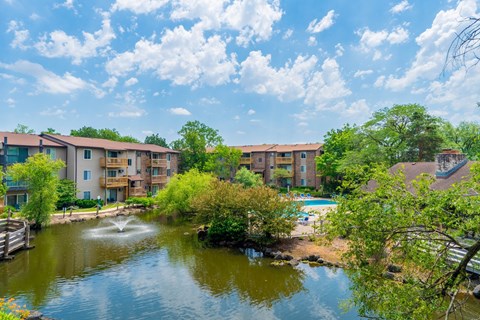 A pond in front of apartment buildings on a sunny day.