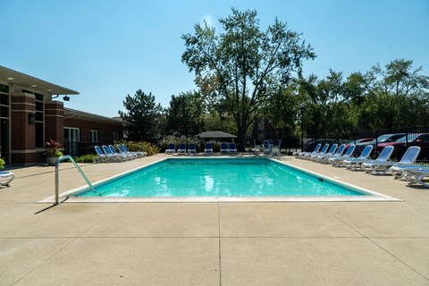 A large swimming pool surrounded by chairs and trees.