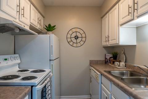 A white stove and oven in a kitchen with a clock on the wall.