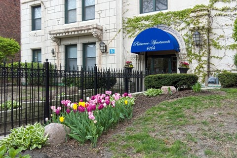 A white building with a blue awning and a black fence.