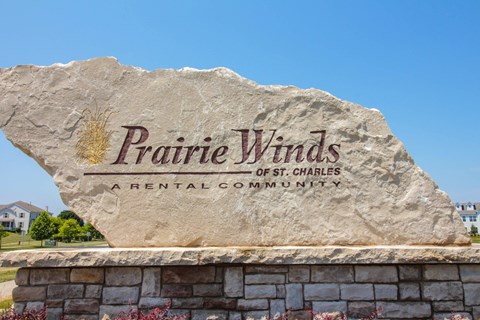 A large stone sign that says Prairie Winds in front of a house.