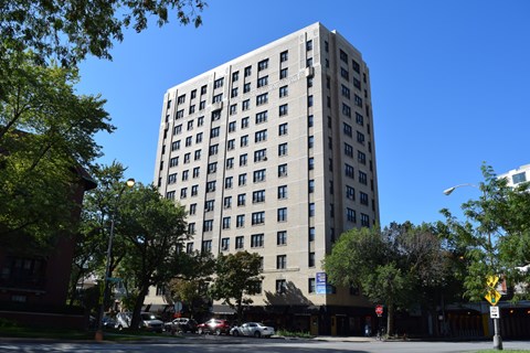 A tall building with many windows is surrounded by trees.
