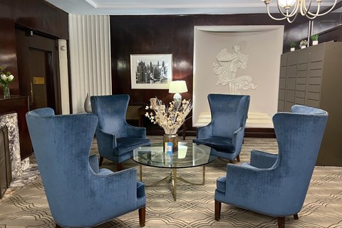 Four blue chairs are arranged around a glass table in a room.
