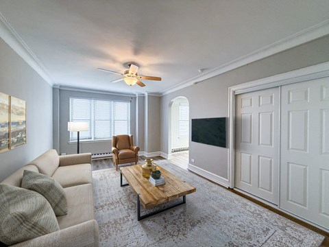 A living room with a beige couch, a wooden coffee table, and a ceiling fan.