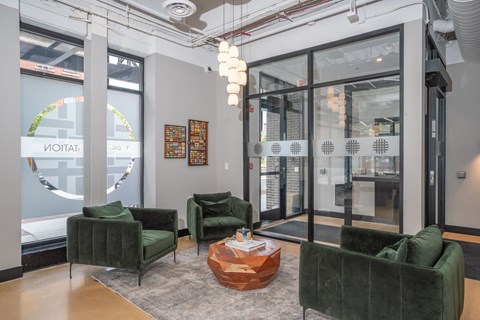 A living room with green velvet chairs and a wooden coffee table.