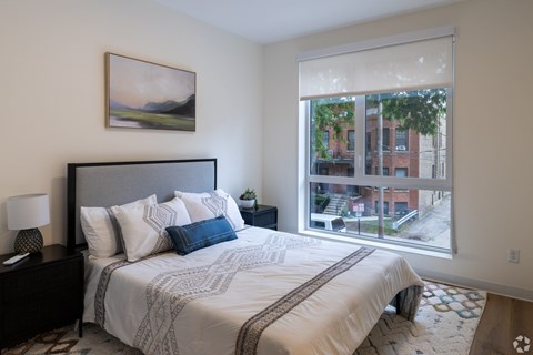 A bedroom with a large bed and a painting on the wall.