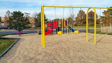 A playground with a yellow swing set and a red slide.
