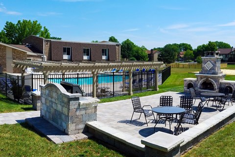 A patio with a table and chairs overlooking a pool.