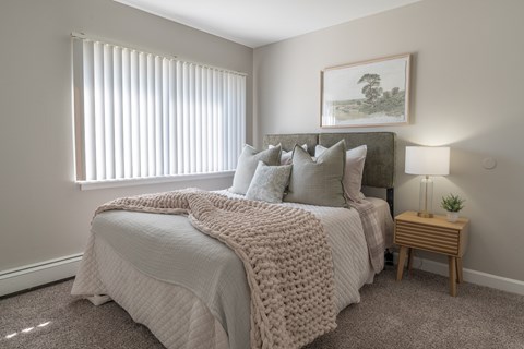 A bedroom with a large bed covered in a white blanket and pillows.