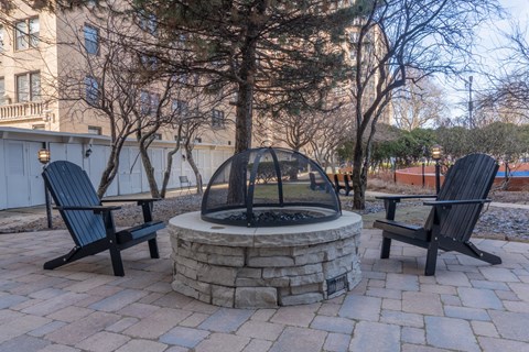 A fire pit surrounded by two chairs on a patio.