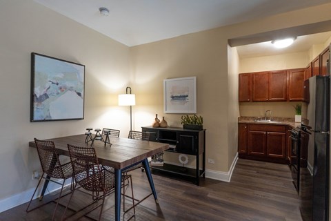 A kitchen with a table and chairs in the foreground and a fridge in the background.