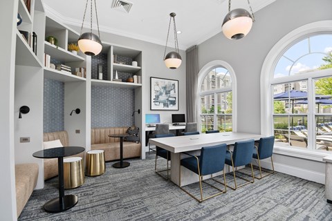 A modern office space with a large desk, chairs, and a balcony with a view of the outside.