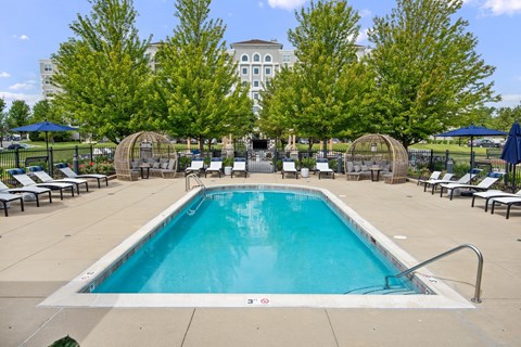 A large swimming pool surrounded by trees and lounge chairs.