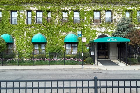 A building with green awnings and a black fence in front.