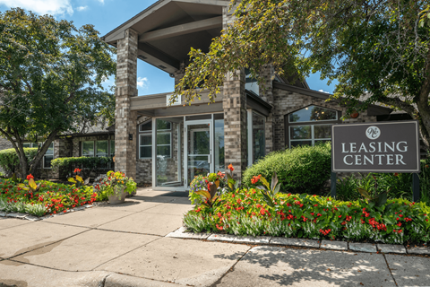 A leasing center is surrounded by flowers and trees.
