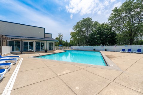 A large outdoor swimming pool with lounge chairs and a building in the background.