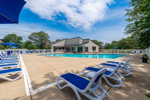 A poolside area with sun loungers and a building in the background.