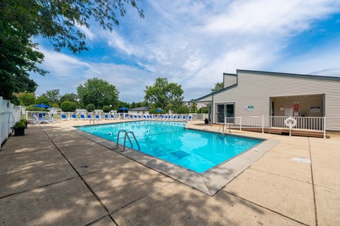 A large outdoor swimming pool with a diving board and a building in the background.