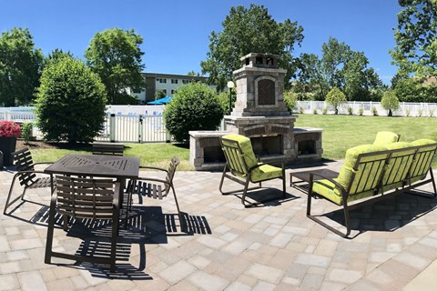A patio with a table, chairs, and a fireplace.