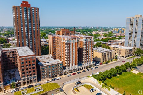A cityscape with a mix of modern and older buildings, a clear sky, and a road with vehicles.
