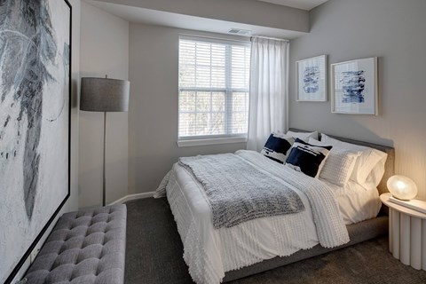 A bedroom with a large bed and a grey tufted bench.