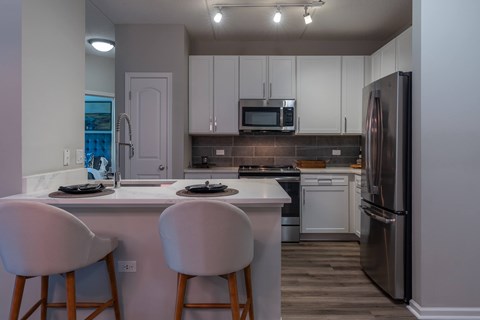 A kitchen with white cabinets and a stainless steel refrigerator.