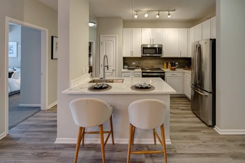 A kitchen with a white countertop and two white chairs.
