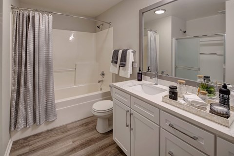 A bathroom with a white toilet, a white sink, and a white bathtub with a shower curtain.
