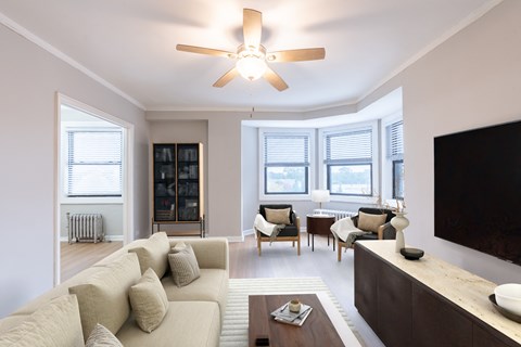 A living room with a beige couch and a ceiling fan.