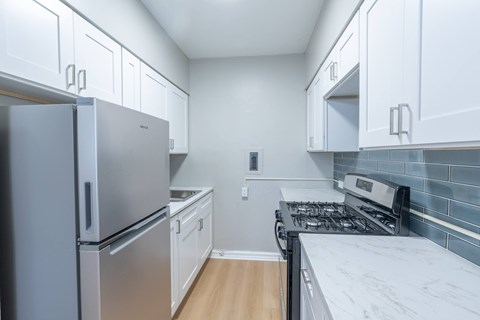 A kitchen with a refrigerator, stove, and cabinets.
