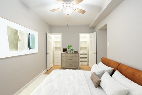 A bedroom with a bed, dresser, and a ceiling fan.