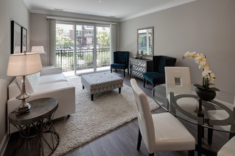 A well-lit, modern living room with a glass table and white chairs.