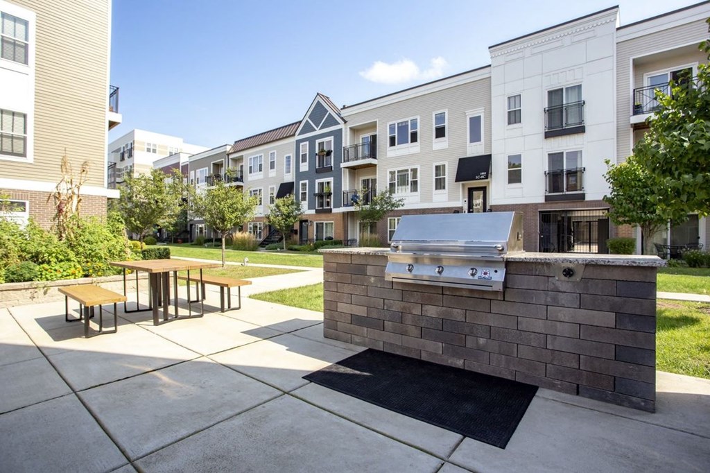 a grilling area with a picnic table in front of an apartment building