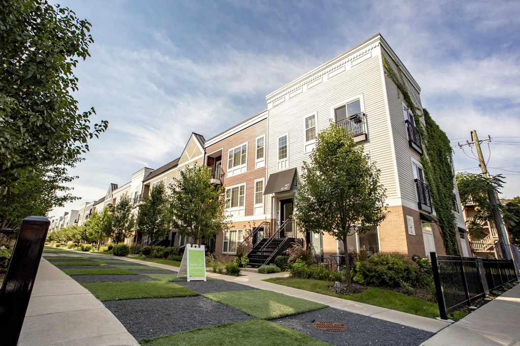 a row of townhouses on a sidewalk with grass and trees