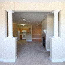 an empty room with pillars and a kitchen in it