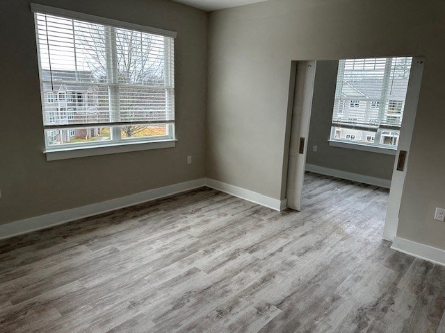 an empty living room with wooden floors and two windows