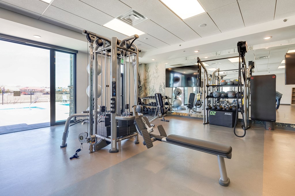 a gym with weights and other exercise equipment and a large window