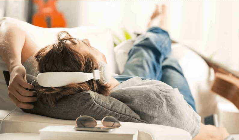 a man laying on a couch wearing a pair of headphones