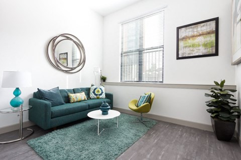 a living room with a blue couch and a green rug