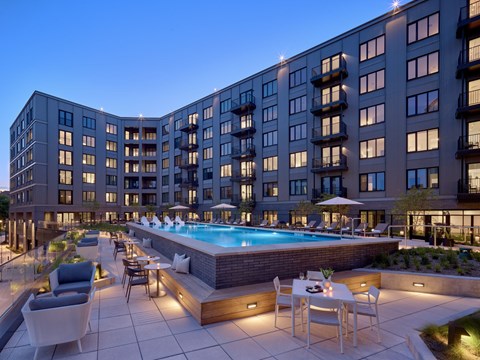 A modern apartment complex with a pool and outdoor seating area.