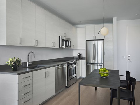 a kitchen with white cabinets and a table with a bowl of fruit
