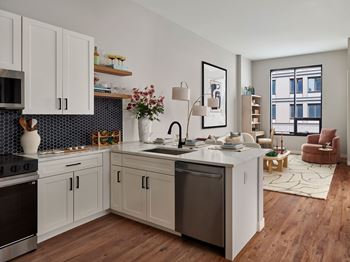 A modern kitchen with wooden floors and white cabinets.