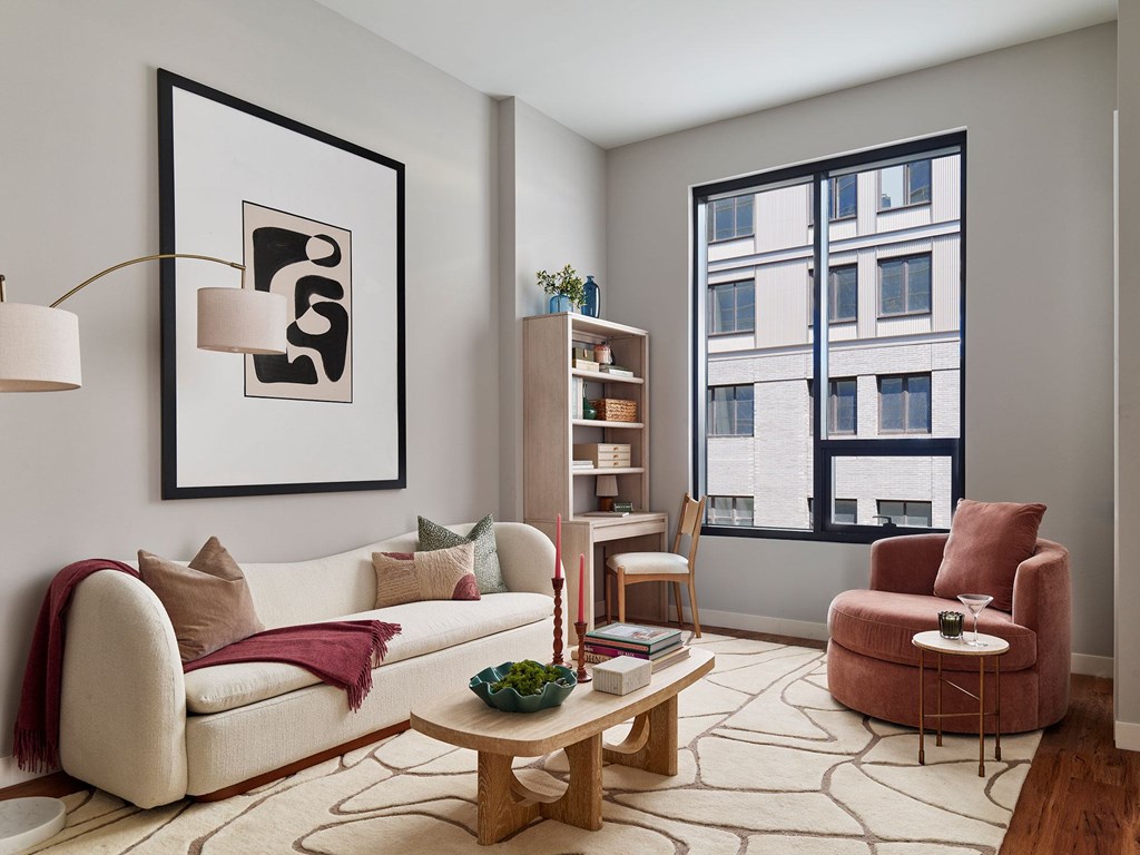 A living room with a white couch, a wooden coffee table, and a red armchair.