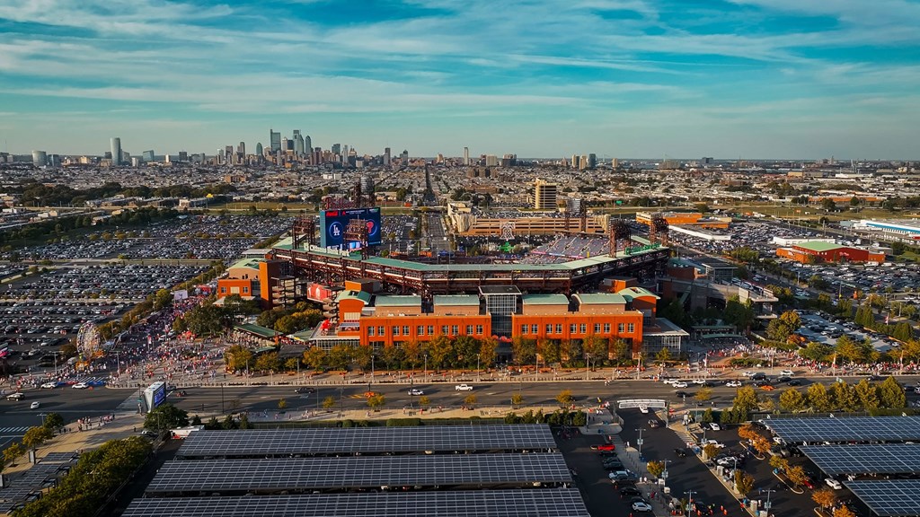A large stadium with a red roof is surrounded by solar panels.