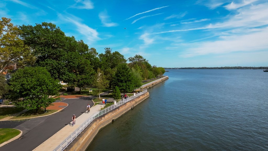 A serene waterfront scene with a clear blue sky and people enjoying the outdoors.