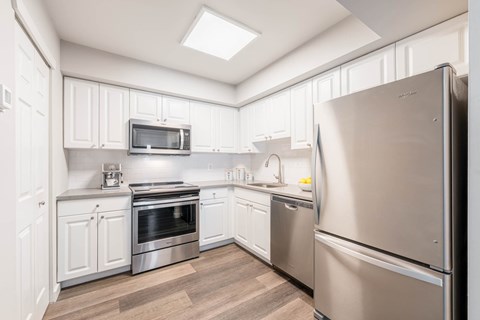 A modern kitchen with stainless steel Whirlpool appliances and white cabinetry.