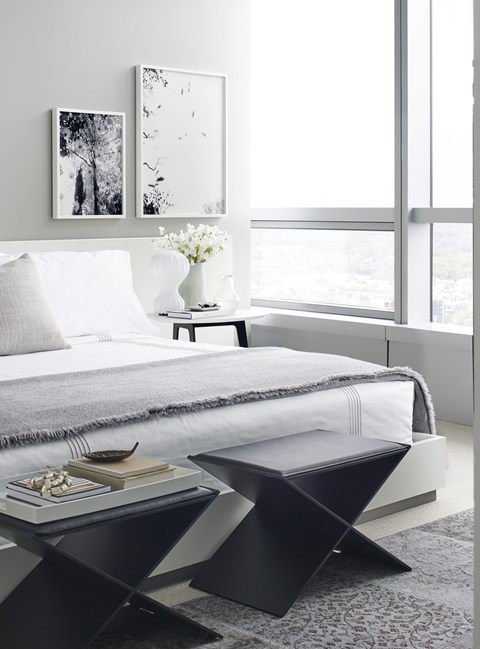 A modern bedroom with a large bed and a small table with a vase of flowers on it.