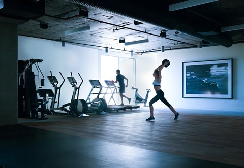 A man is working out in a gym with a woman.