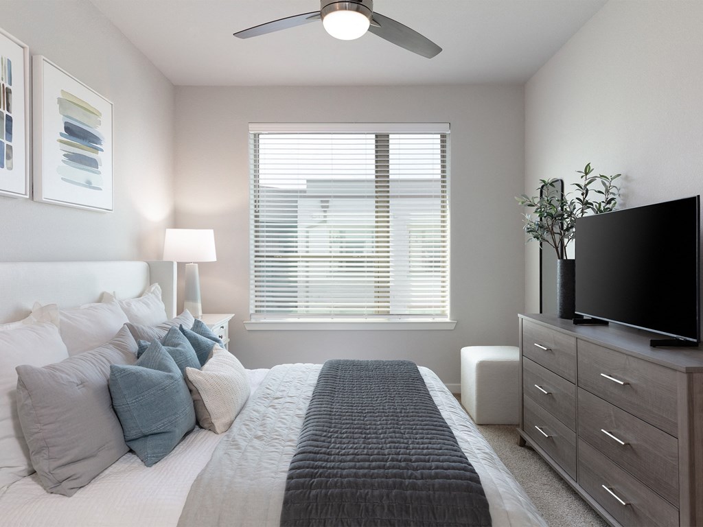 a bedroom with a large bed and a dresser with a tv on top of it