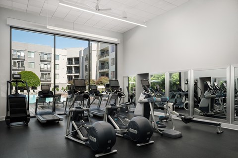 A gym with a view of apartment buildings outside the large windows.